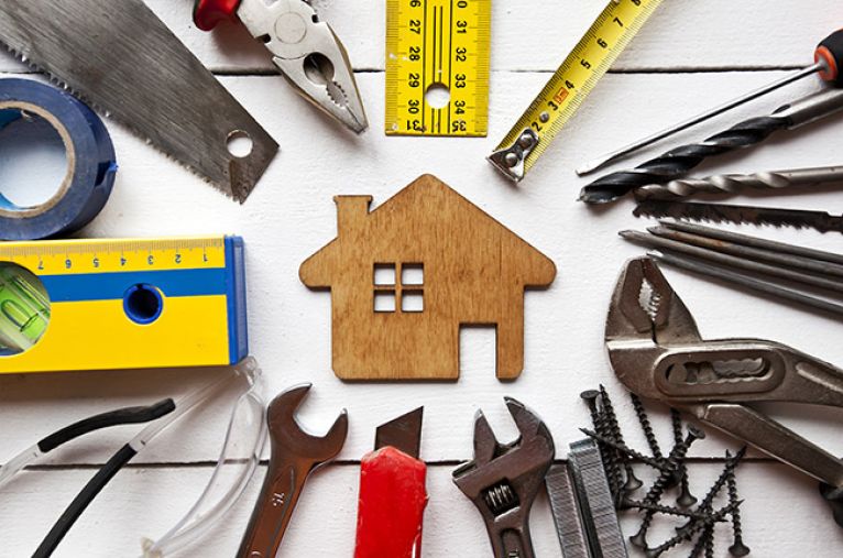 Wooden house cut-out surrounded by tools