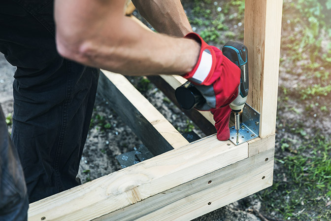 Carpenter installing corner joint brace on shed